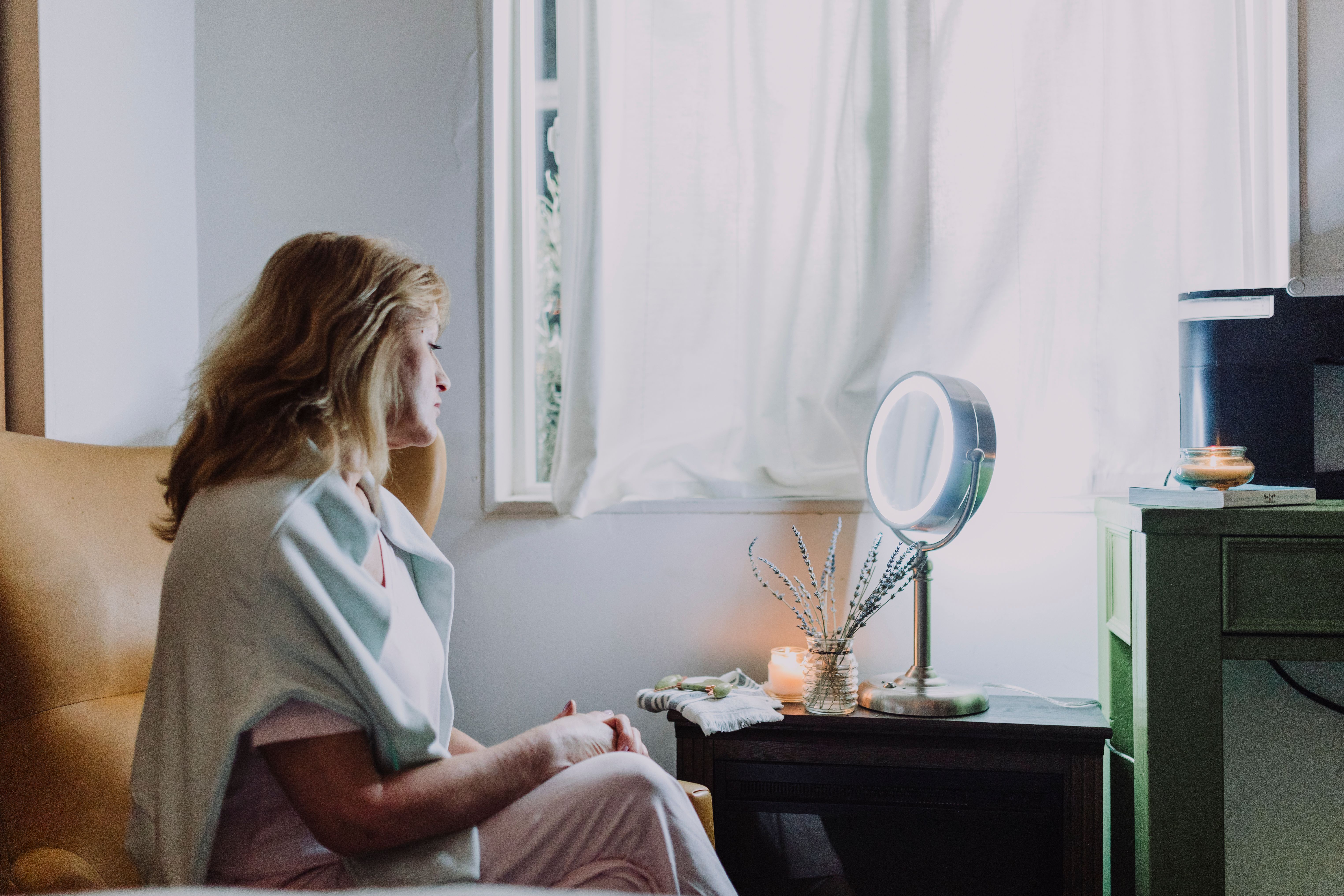 A woman in her early fifties sitting calmly by a window in soft natural light, reflecting on changes in libido during menopause