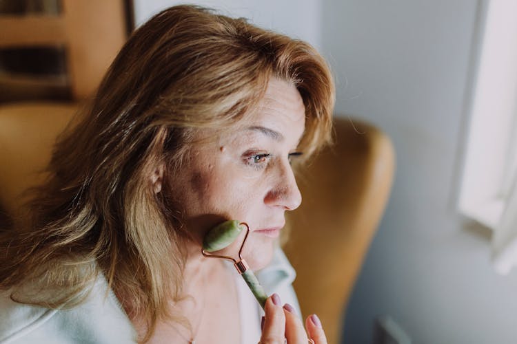 A Woman Using A Face Roller 