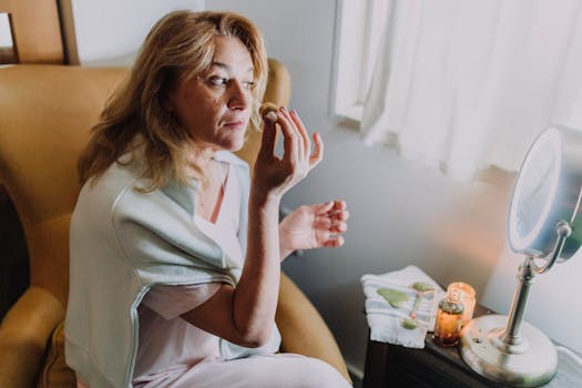 Woman indulging in self-care with a jade roller and candlelight ambiance indoors.
