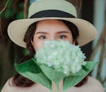 一幅迷人的肖像，描绘了一位戴草帽、手持绣球花的年轻女子