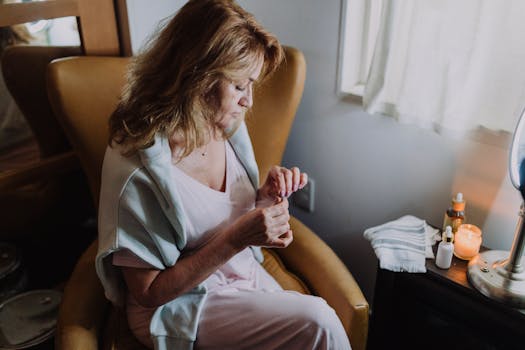 A senior woman relaxes indoors engaging in a calming self-care routine by candlelight.