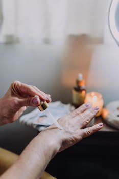 Close-up image of a hand applying skin care serum using a dropper. Indoor setting with warm lighting.