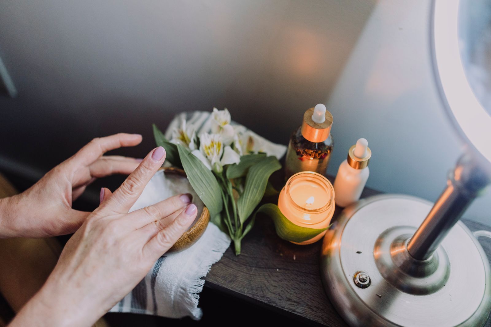 Mains du thérapeute posées sur le visage d'une cliente, lumière naturelle douce de fenêtre