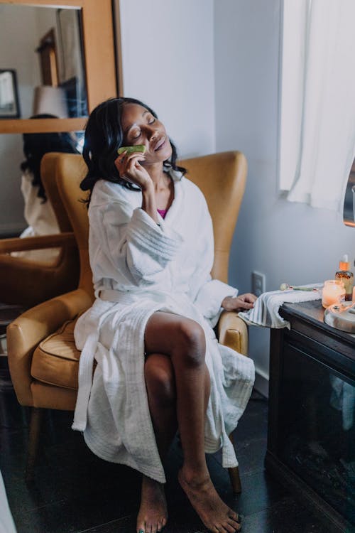 A Woman Wearing  White Robe Scraping  Face with a Gua Sha