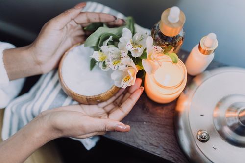 Free A calming spa scene featuring hands holding flowers beside candles and skincare products. Stock Photo