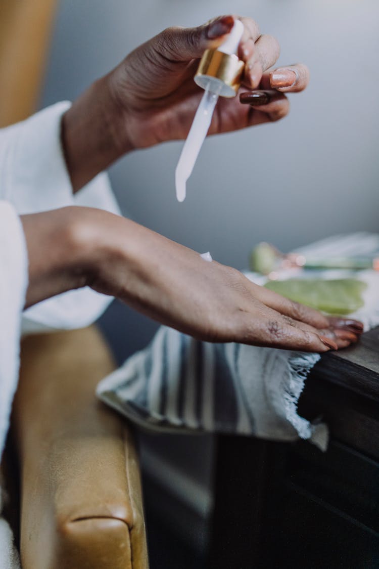 A Person Applying Cosmetic Product On Hand With A Dropper