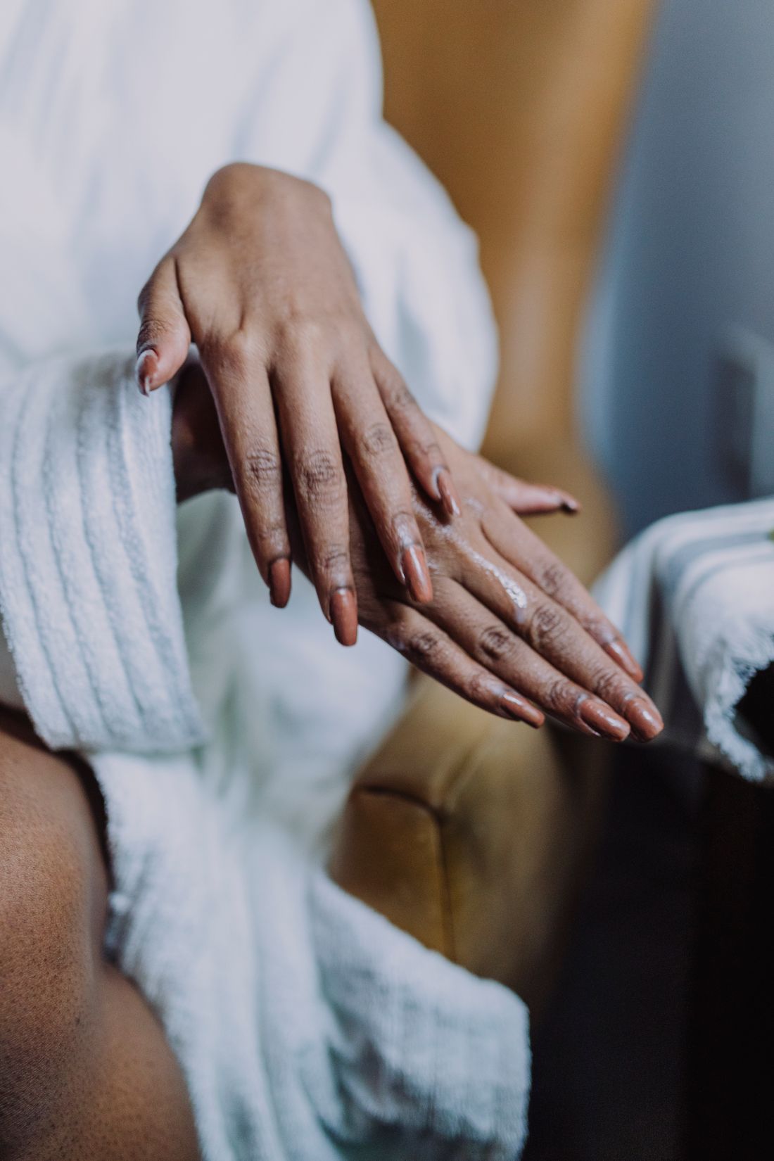 Hands being cared for with moisturizer in a calm, warm setting