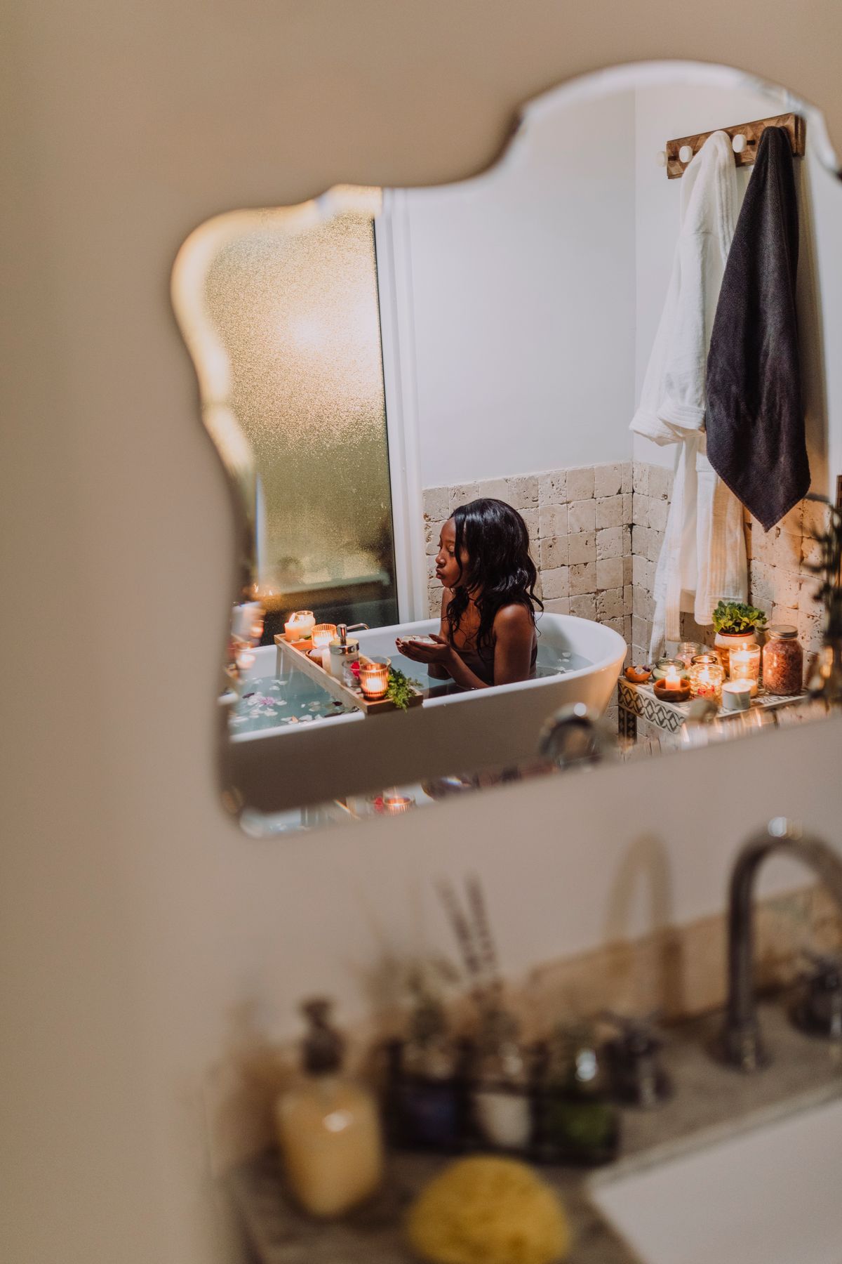 Woman relaxing in a candlelit bath as part of her self-care ritual