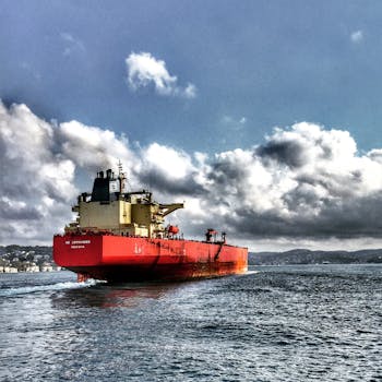 Red cargo ship navigating the Bosphorus under dramatic clouded sky, Turkey.