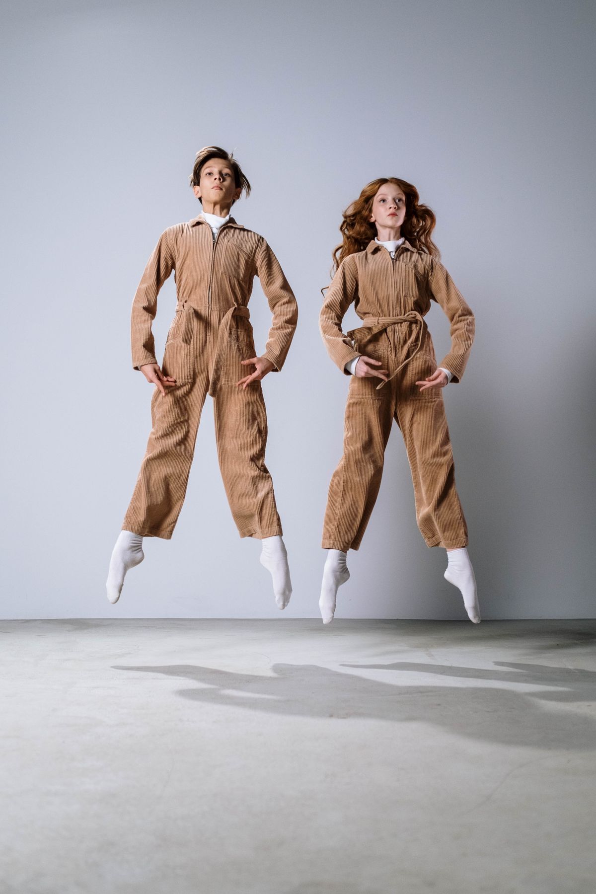 Boy and girl in brown corduroy suits jumping