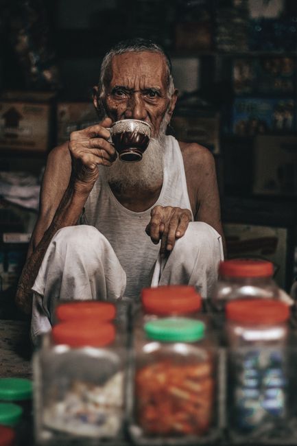 mobile phone care tips - Recommended Accessories for Mobile Phone Maintenance | An elderly man sipping tea inside a traditional Pakistani market store.