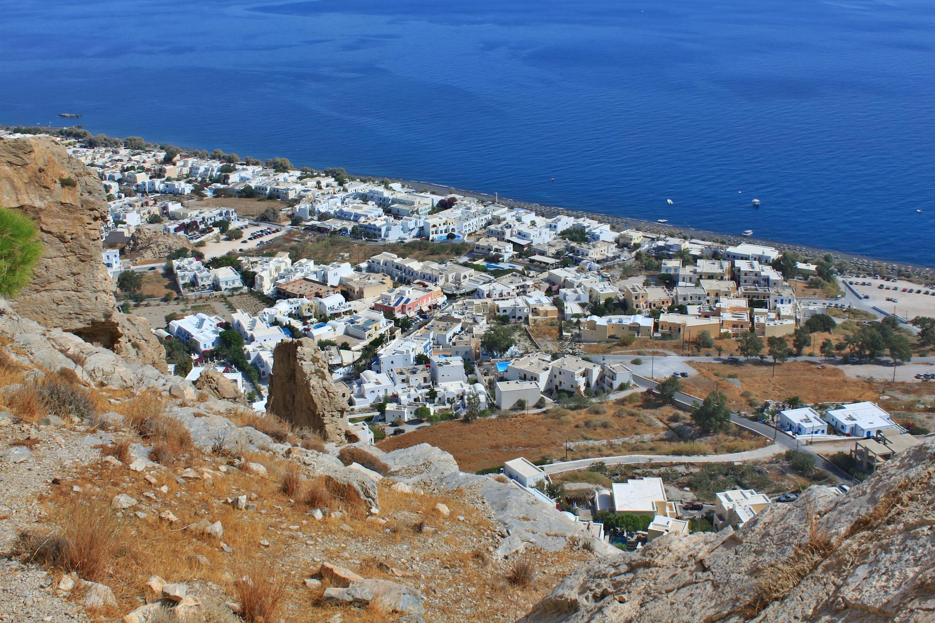 Aerial view of Santorini's white-washed buildings against a deep blue sea, capturing Greek island charm.