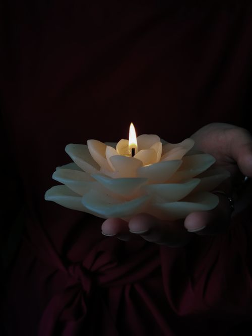 Free A serene scene with a flower-shaped candle held gently in hand, glowing softly in the dark. Stock Photo
