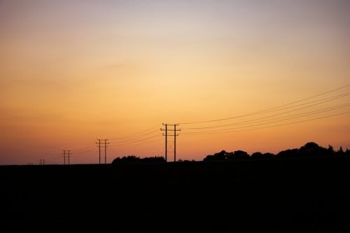 Silhouetted Electricity Lines and Utility Poles at Sunset 