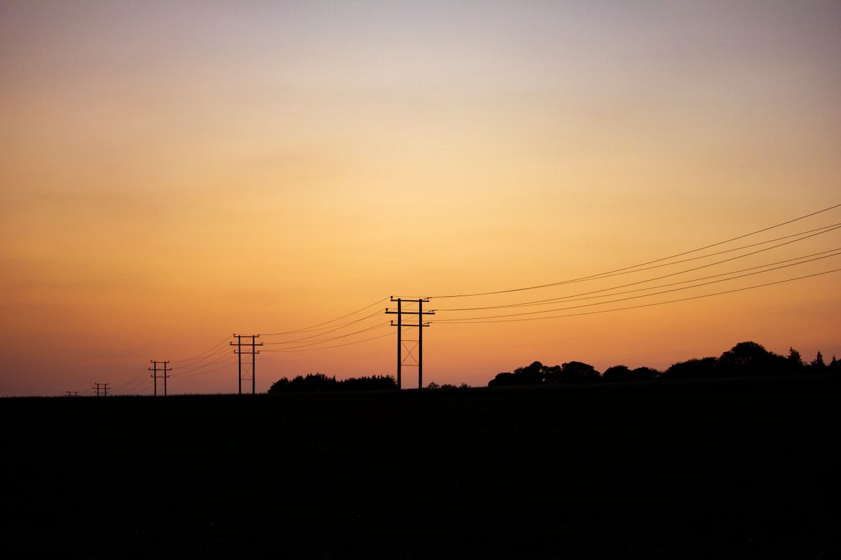 Power lines and utility poles at sunset, part of the electric grid NV Energy serves across Southern Nevada