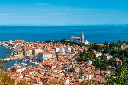 A stunning aerial view of Piran, Slovenia, showcasing the picturesque harbor and historic architecture under a bright summer sky.