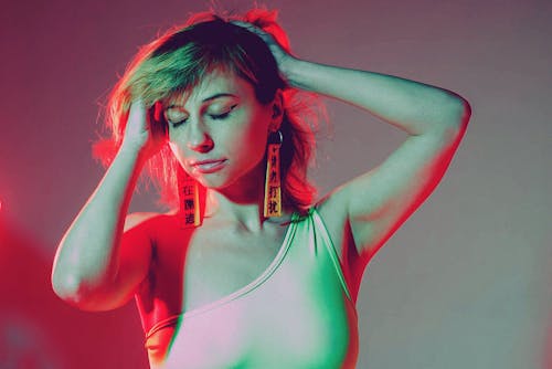 Alluring young lady dancing with closed eyes in neon illumination