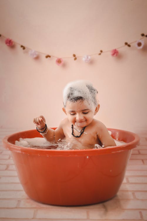 Free Baby in Red Plastic Bathtub Stock Photo