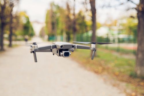 Free A focused image of a drone flying outdoors in a public park with blurred surroundings. Stock Photo
