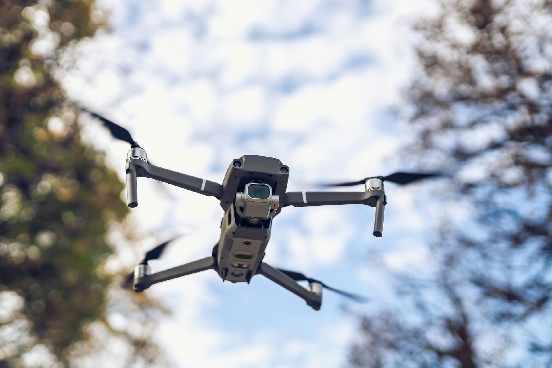 Close-up view of a drone flying outdoors against a vibrant blue sky. Captures modern technology in action.