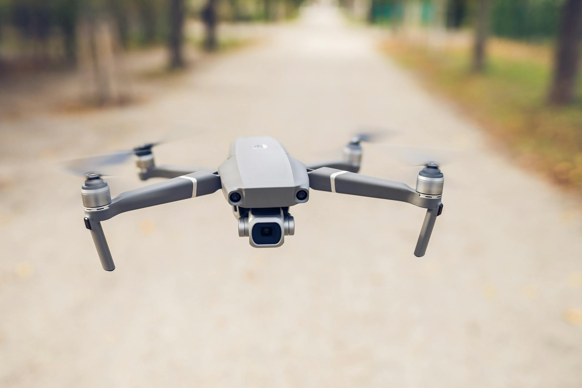 A sleek, modern drone captured flying outdoors in a serene park setting.