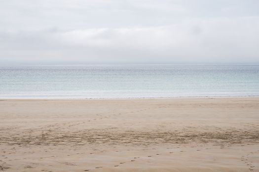 Tranquil beach scene with calm ocean waters and cloudy sky, perfect for relaxation themes.