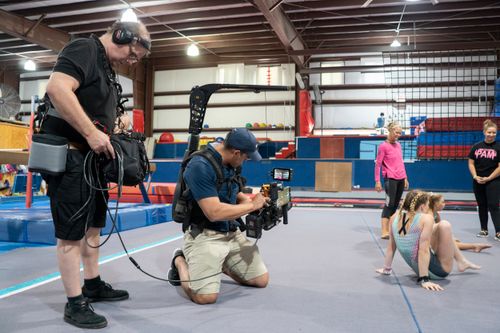 Free Cameramen in a gymnasium capturing footage of young gymnasts during practice in Miami. Stock Photo