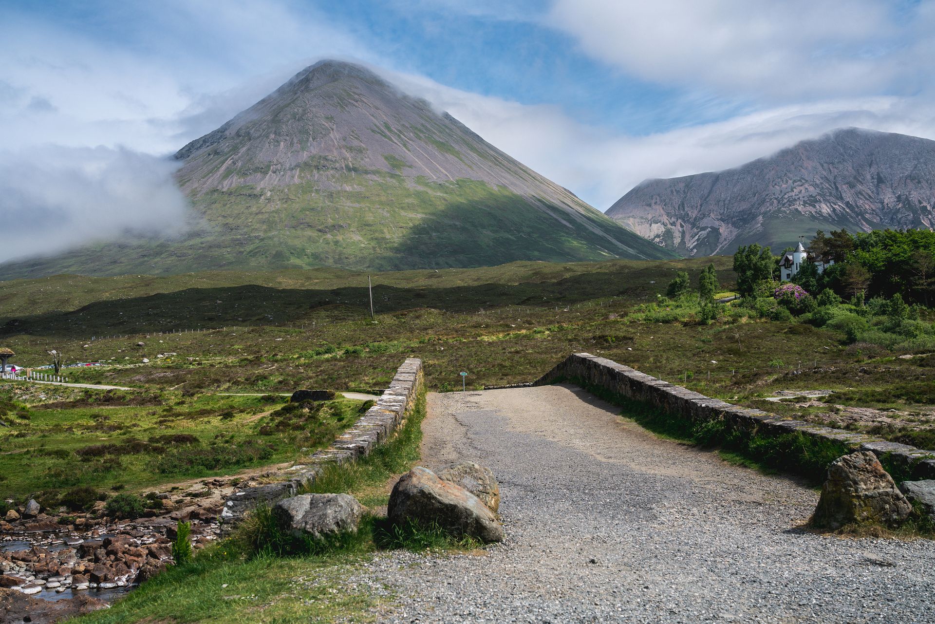 Picturesque landscape of the Scottish Highlands featuring mountains, a stone road, and lush greenery.