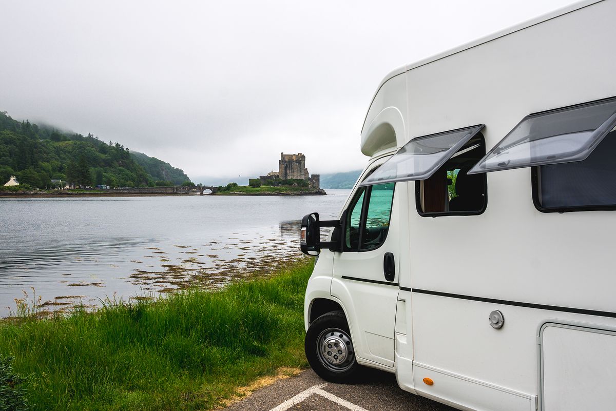 Touring coach parked beside a castle loch