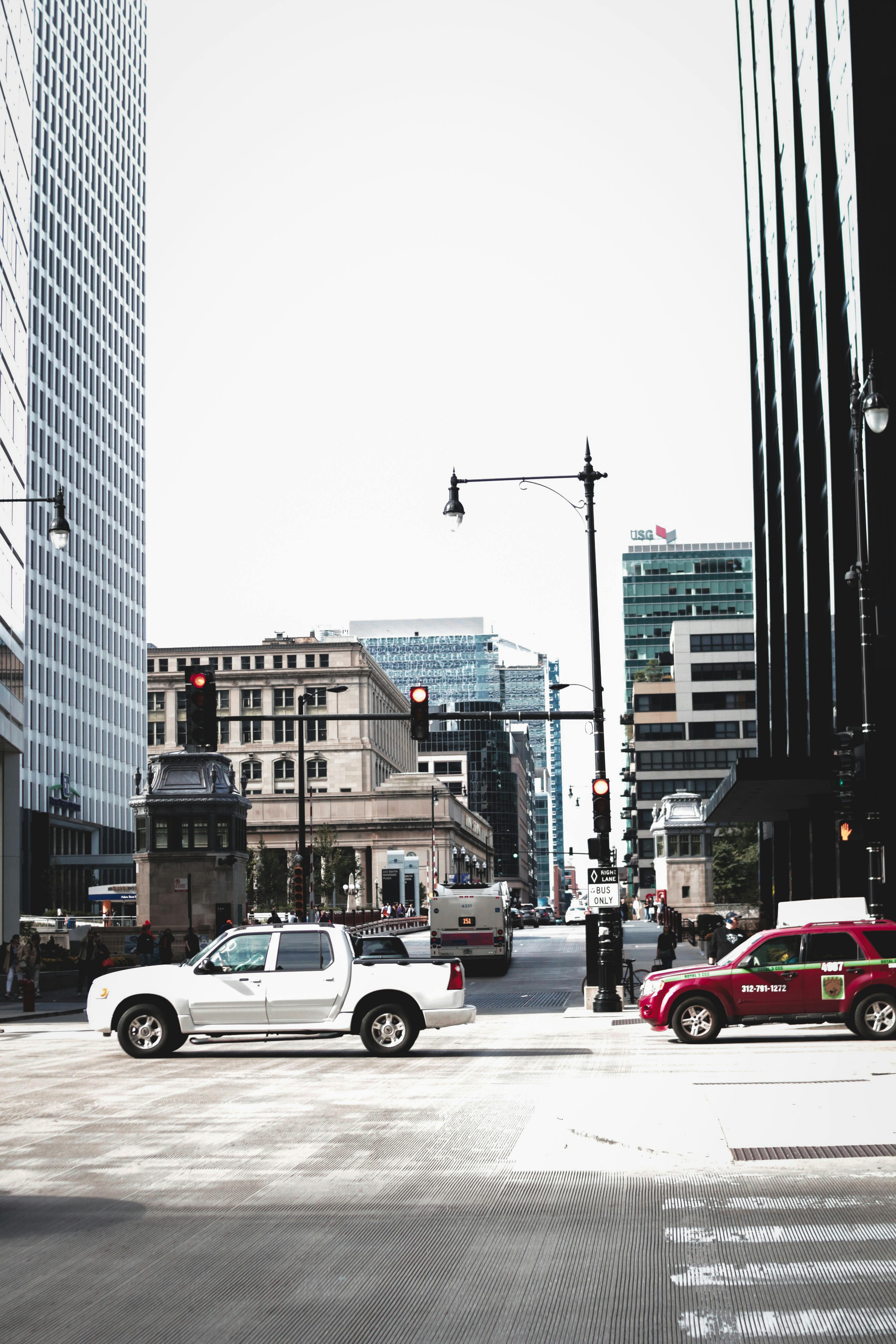 City street intersection with cars and skyscrapers under a clear sky.