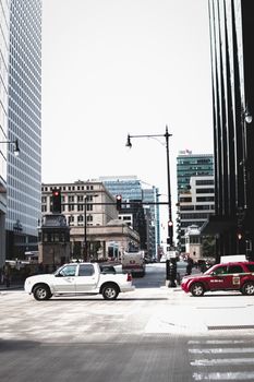 City street intersection with cars and skyscrapers under a clear sky.