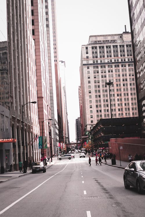 Photo of People Crossing Through Street in the Middle of Buildings