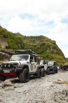 Rugged off-road jeeps navigate rocky terrain in scenic Philippine mountains, capturing the essence of adventure travel.