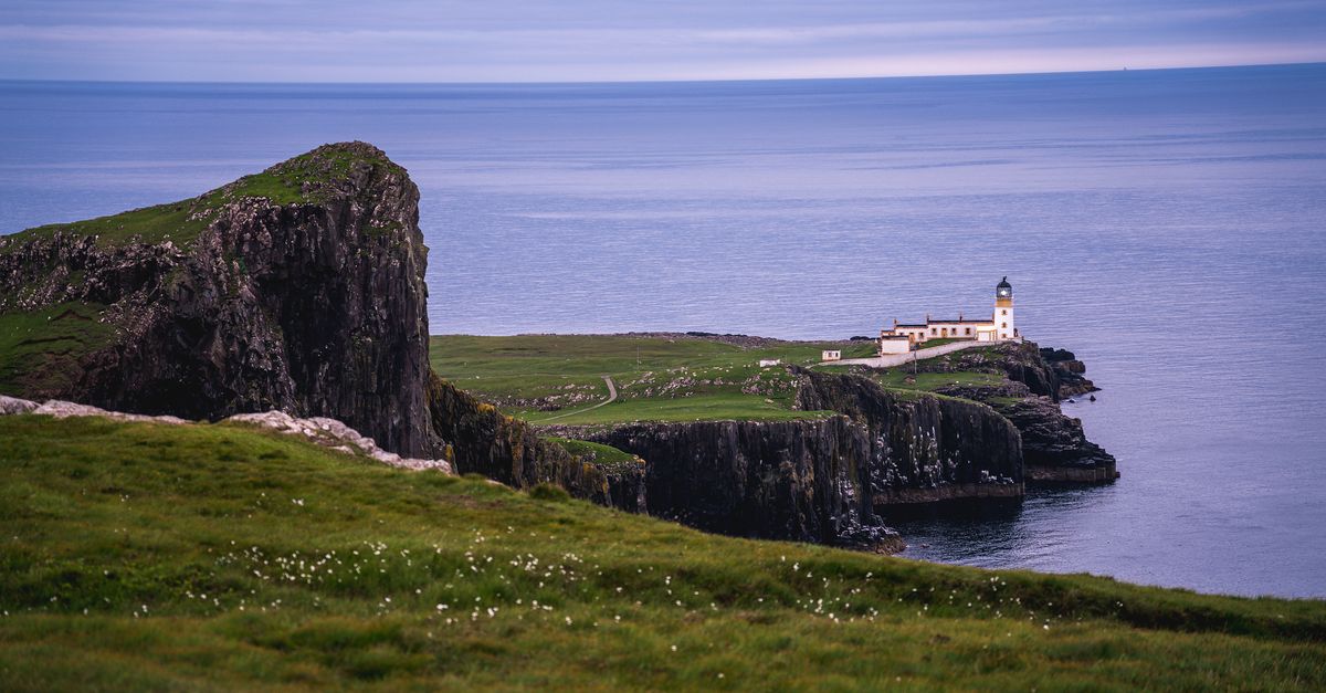 A stunning view of a lighthouse perched on rugged cliffs against the sea in Scotland.