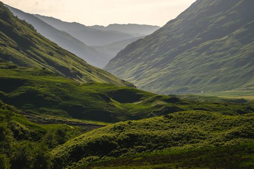 Free Explore the tranquil beauty of a lush green valley surrounded by rolling hills and a peaceful sky. Stock Photo