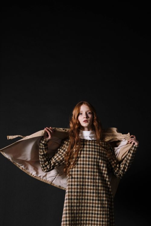 Free Teen girl in a plaid dress striking a pose in studio with a dark background. Stock Photo