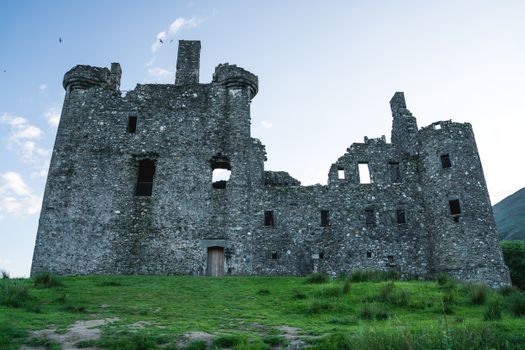 Scenic view of Kilchurn Castle ruins surrounded by grass, a testament to Scottish history.