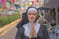 A joyful nun in prayer outdoors with vibrant flags in a lively setting.