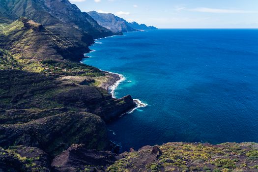 Scenic aerial view of rugged coastline meeting vibrant blue ocean, capturing natural beauty.