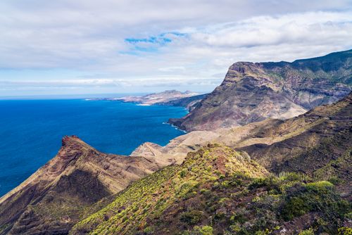 Free Breathtaking aerial view of a coastal mountain range with deep blue ocean and vibrant greenery. Stock Photo