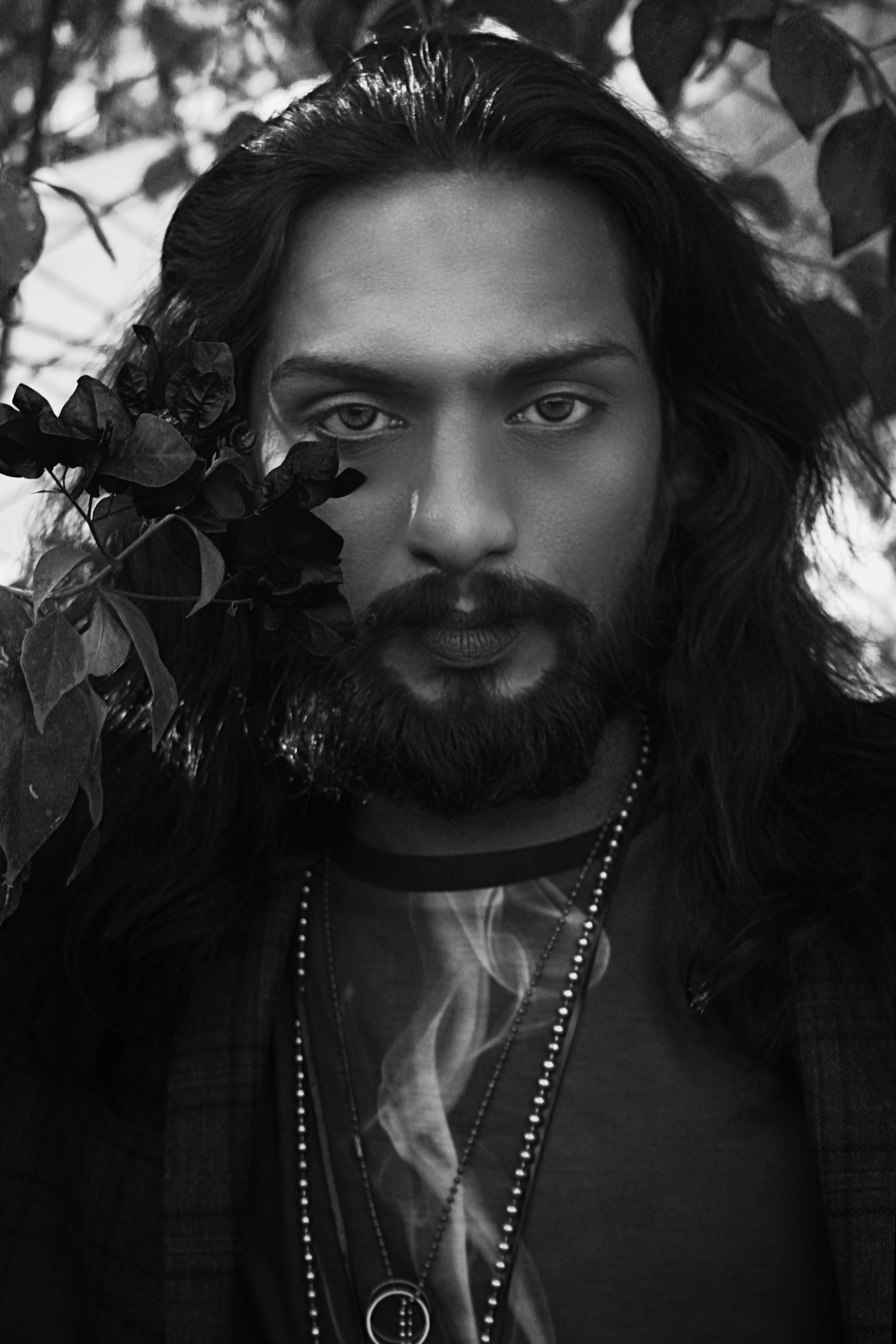 Grayscale portrait of a stylish man with long hair in a natural setting, Madrid.