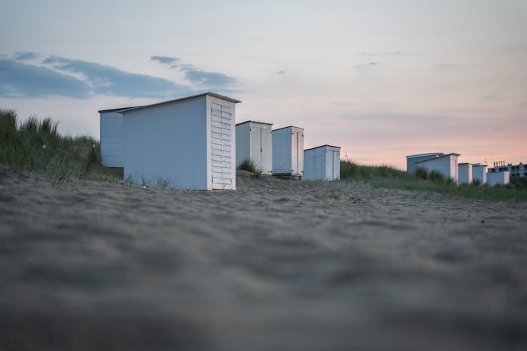 Low Angle View Of Sheds On Sandy Beach At Dusk