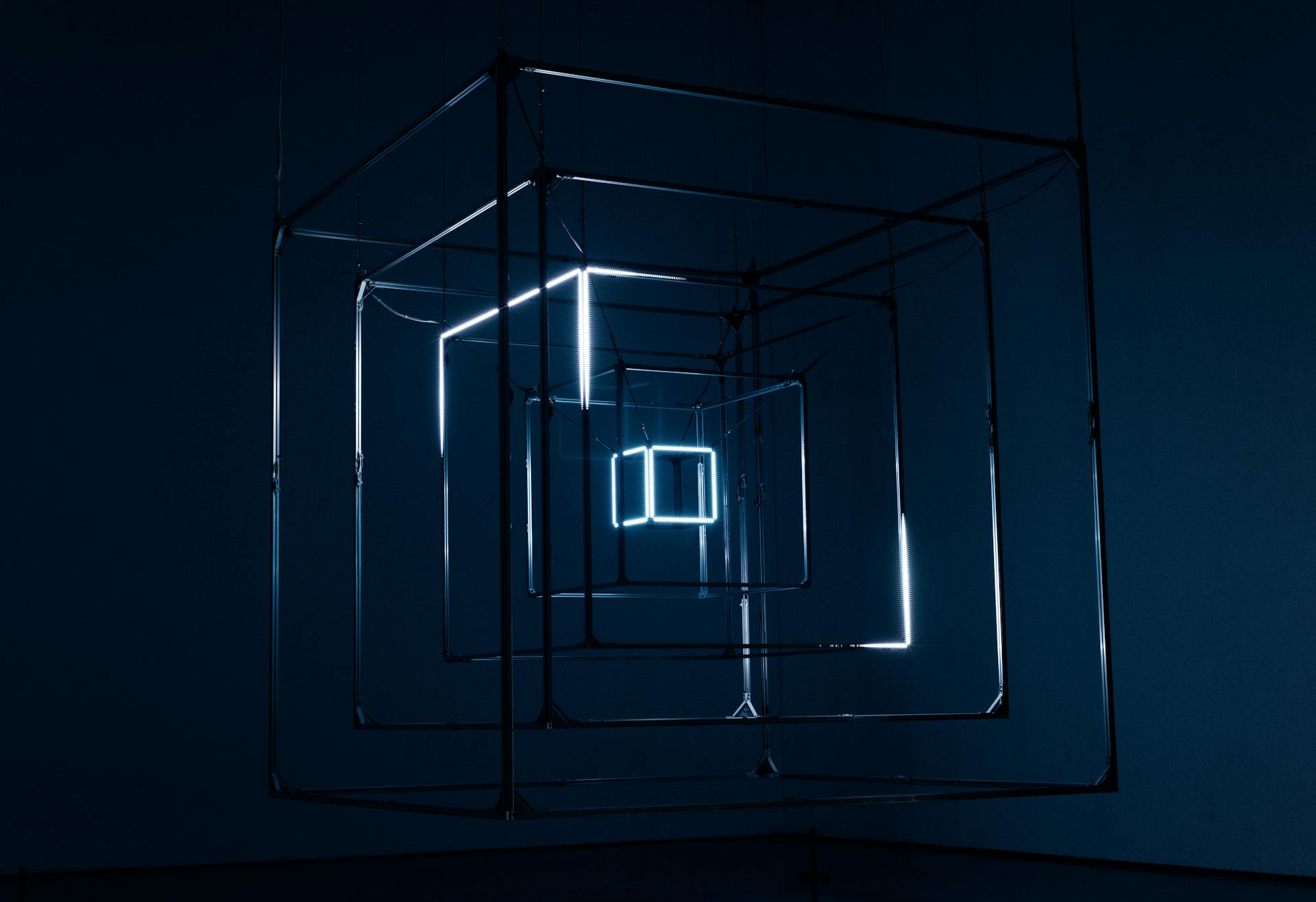 A captivating geometric light installation using cubes and neon lights against a dark background.