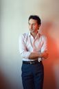 Thoughtful adult male entrepreneur in formal wear with folded arms looking away against wall with shade