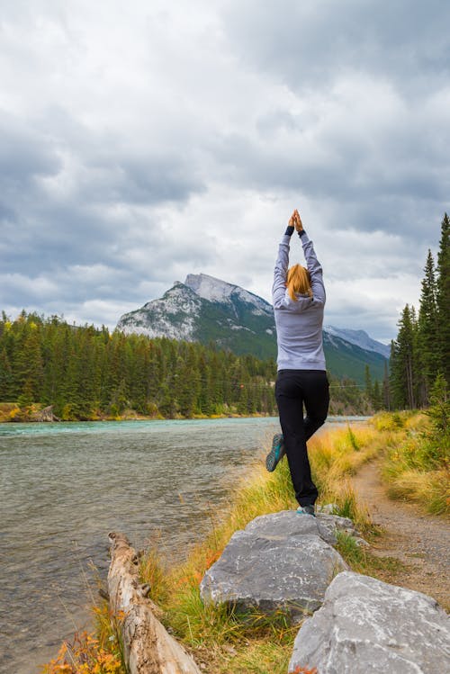 Woman in a Yoga Pose on a Riverbank
