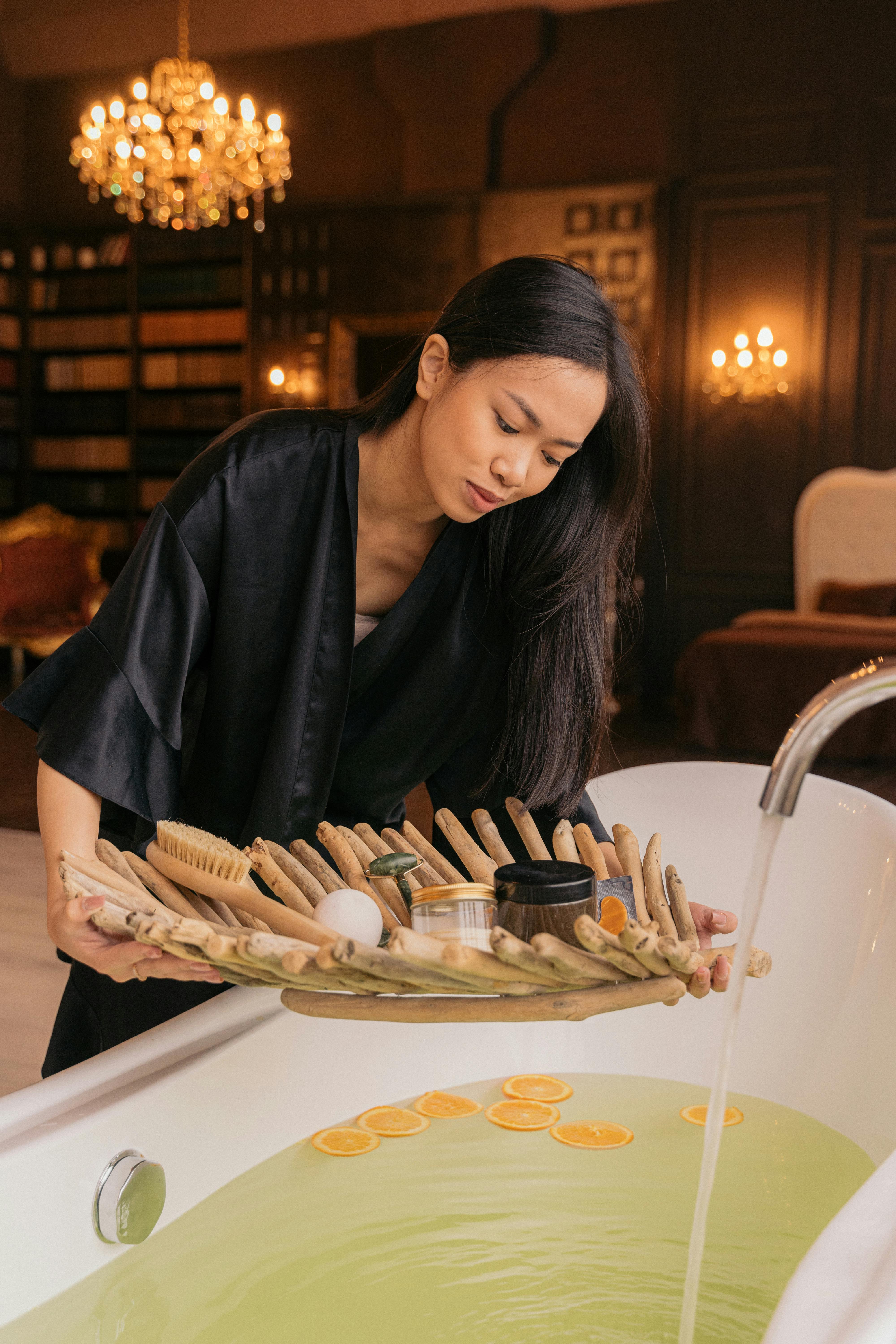 woman running herself a bath and carrying a tray with beauty products