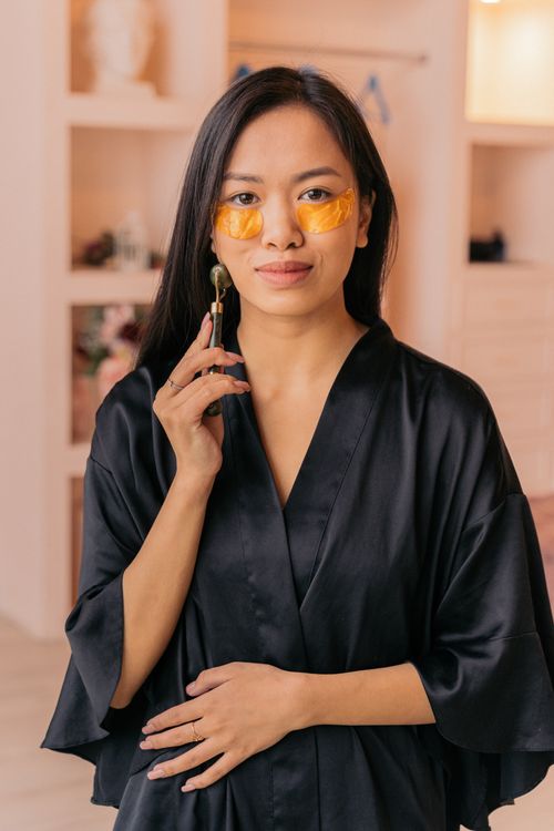 Free Woman wearing under eye patches using a facial roller indoors Stock Photo