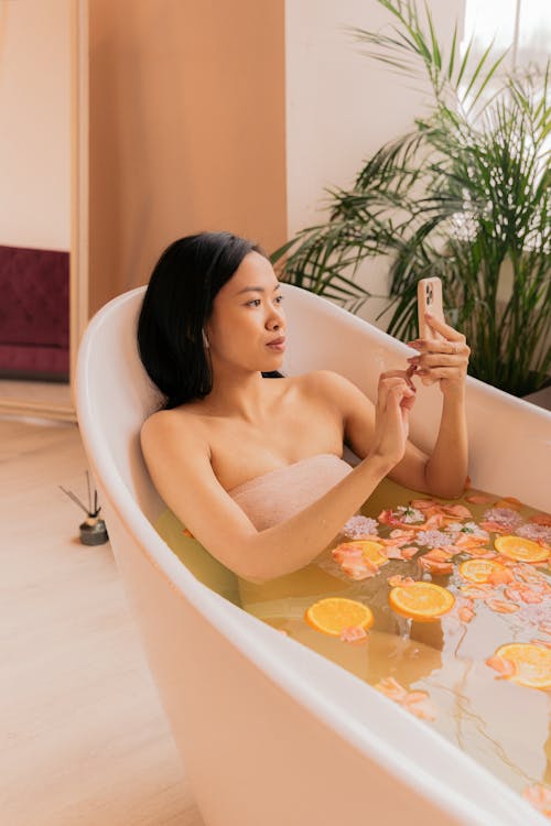 Free Woman Taking a Flower Bath and Using Her Phone  Stock Photo