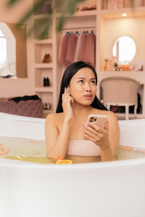 Woman Taking a Bath and Listening to Music on Earphones 