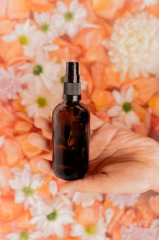 Hand holding a cosmetic bottle against a vibrant floral backdrop.